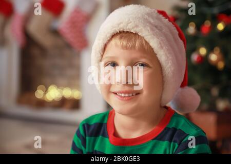 Cute little boy in Santa Claus hat at home Stock Photo