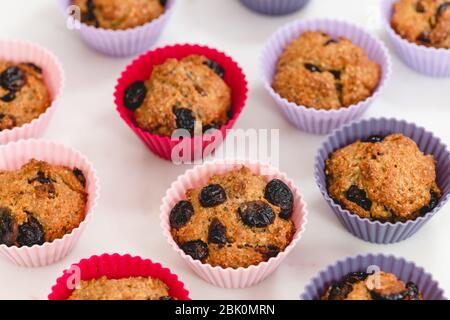 Bran muffins with dry cranberries close up in baking silicon cups on white background. Healthy food, good source of dietary fiber Stock Photo