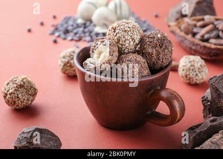 Cup with tasty sweet truffles on color background Stock Photo