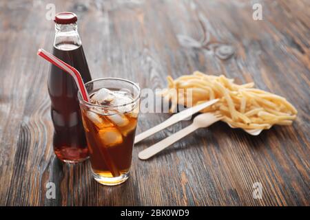 Cold cola and tasty french fries on wooden table Stock Photo