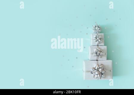 Christmas banner. Xmas silver and glitter gifts box, blue background. Christmas gift boxes laid out in the shape of a Christmas tree, overhead view Stock Photo