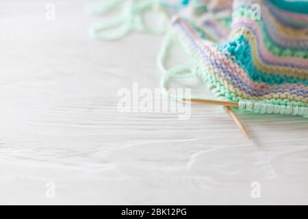 Knitted colored striped fabric. Yarn for knitting pastel colors. Whitr painted wood background. Stock Photo
