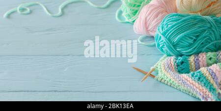 Knitted colored striped fabric. Yarn for knitting pastel colors. Blue painted wood background. Stock Photo