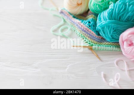 Knitted colored striped fabric. Yarn for knitting pastel colors. Whitr painted wood background. Stock Photo