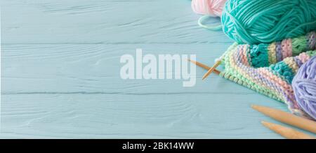 Knitted colored striped fabric. Yarn for knitting pastel colors. Blue painted wood background. Stock Photo