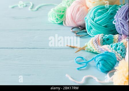 Knitted colored striped fabric. Yarn for knitting pastel colors. Blue painted wood background. Stock Photo