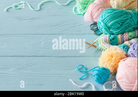 Knitted colored striped fabric. Yarn for knitting pastel colors. Blue painted wood background. Stock Photo