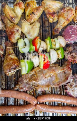 Chicken, pork meat, sausages and vegetables on a skewer on the barbecue. Stock Photo