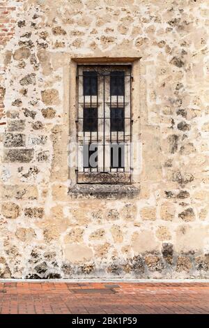 Old yellow stone wall with small window and bars on it. Vertical background photo texture Stock Photo
