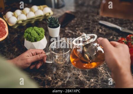 Man filling a mug with black tea Stock Photo