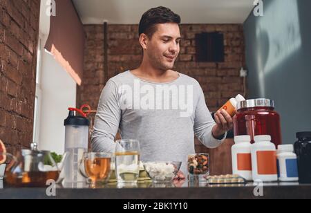 Fit man examining a dietary supplement in his hand Stock Photo