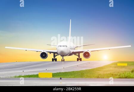 Large aircraft on taxiing sunset at the airport, the sky is the sun and the steering track. Stock Photo