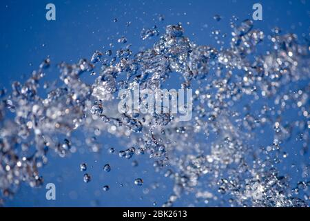 Water droplets spraying from a fountain in abstract design on blue sky background and detail and contrast. Concept. Stock Photo