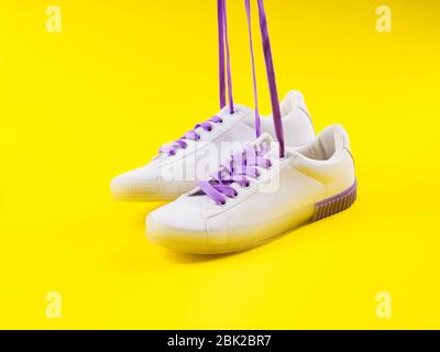 White sneakers with purple laces on yellow background Stock Photo