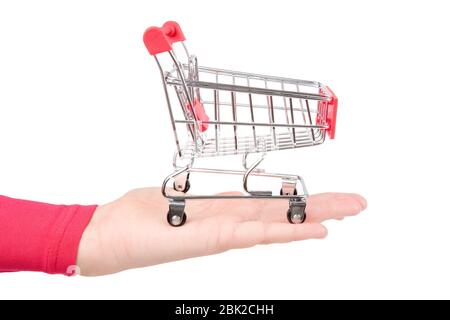 Empty miniature supermarket shopping trolley stands on a female palm. Close-up shot, isolated on white. Stock Photo