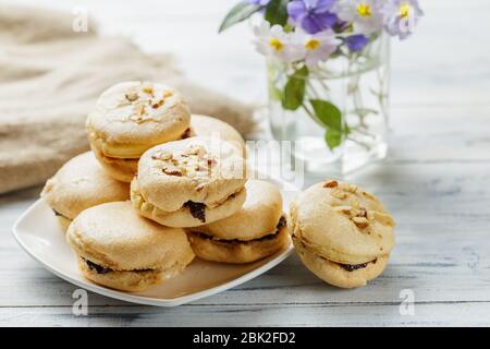 Butter cookies with jam on white wooden background with flowers on the background Stock Photo