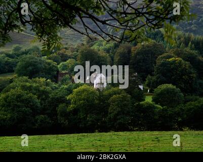 View SW of Capel-y-ffin monastery, Llanthony, Powys, Wales, UK: ruined Abbey Church (L), monastery quadrangle (centre) & statue of Blessed Virgin Mary Stock Photo