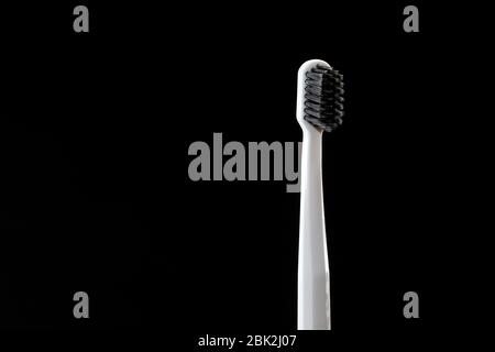 gray toothbrush with black bristles isolated on black background. copy space for text. concept of healthcare. dental care concept. selective focus Stock Photo