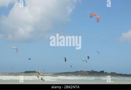 Windsurfers and kite surfers enjoy windy conditions on a beach near Santec in northern Brittany, France. Stock Photo