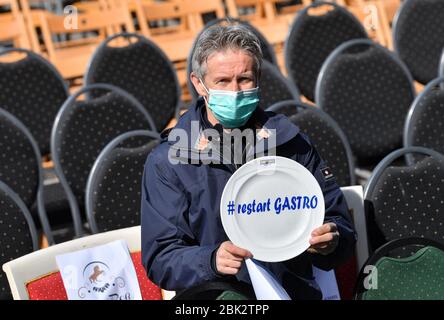 Oberwiesenthal, Germany. 01st May, 2020. Jens Weißflog, ski jumping world champion, Olympic champion and hotelier, takes part in the nationwide 'Empty Chairs' campaign of restaurateurs and hoteliers in Oberwiesenthal and holds a plate with the inscription '#restart Gastro'. In total, entrepreneurs with more than 900 chairs took part in the protest in the Erzgebirge. The restaurateurs demand massive support from the federal and state governments. Hotels and restaurants are currently closed due to the Corona crisis. Credit: Hendrik Schmidt/dpa-Zentralbild/ZB/dpa/Alamy Live News Stock Photo