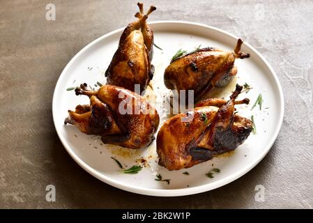 Roasted quails on white plate. Close up view Stock Photo