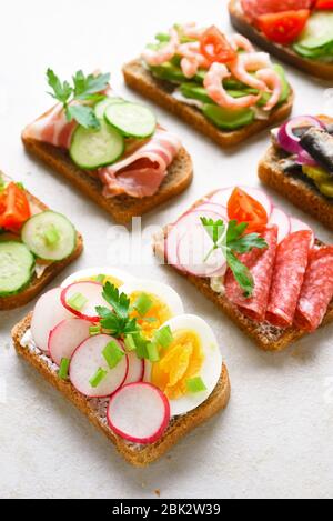 Assortment open sandwiches on light stone background. Tasty healthy snack. Close up Stock Photo