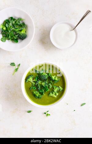Healthy broccoli green pea cream soup in bowl over light stone background. Diet detox food concept. Top view, flat lay Stock Photo