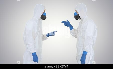 Doctors or scientists in hazamat suits meet and shake hands on gradient background. Stock Photo