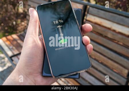 Smartphone charging without cable from induction power bank in the male hand. Modern technology concept. Stock Photo