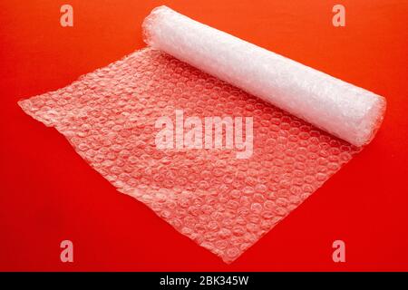 Clear plastic bubble wrap packaging stretched out over a plain red background - studio shot Stock Photo