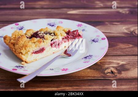 cherry crumble cake on a plate with a fork on wooden background Stock Photo