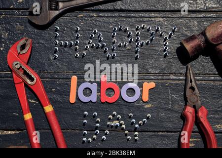 Happy Labor day text in multi color on wooden background with construction repair tools. Labor day concept sign. Stock Photo