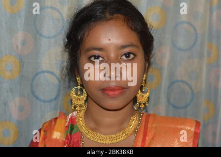 Close up of an beautiful Indian Girl wearing traditional big golden earrings and necklace, selective focusing. Stock Photo