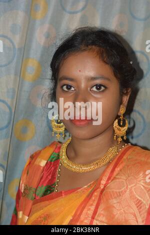 Close up of an beautiful Indian Girl wearing traditional big golden earrings and necklace, selective focusing. Stock Photo