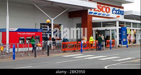 A queue of shoppers respecting social distancing waiting to enter a Tesco Extra supermarket at Sprowston, Norfolk, England, United Kingdom. Stock Photo