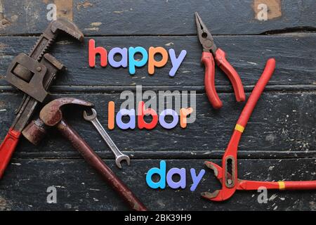 Happy Labor day text in multi color on wooden background with construction repair tools. Labor day concept sign. Stock Photo