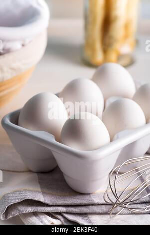 Farm freshly picked organic chicken eggs in a ceramic container or tray on a blurred kitchen background, copy space. Healthy natural food concept. Stock Photo