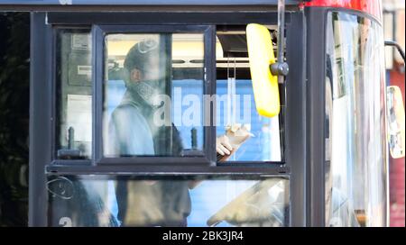 London, UK. 1st May 2020 London Bus Driver prepares to leave his stand /stop by getting his gloves and improvised mask in place  Andrew Fosker / Alamy Live News Stock Photo