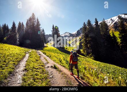 Tourist in orange shirt with backpack walking in the mountains. Outdoor travel concept Stock Photo