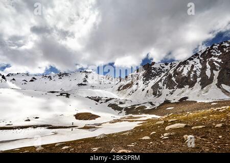 Landscape of snow mountain valley and lake against cloudy sky in Kazakhstan Stock Photo