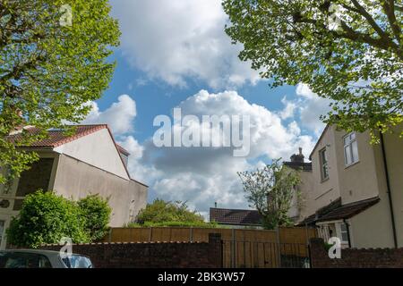 a close up view of the clouds in the blue sky though the middle of two buildings in a small village Stock Photo