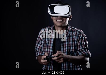 Student man wearing virtual reality goggles in studio,Smartphone using with VR headset. Stock Photo