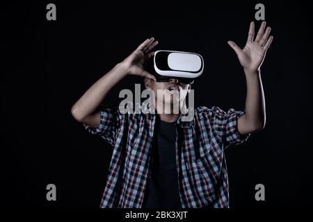 Student man wearing virtual reality goggles in studio,Smartphone using with VR headset. Stock Photo