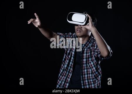 Student man wearing virtual reality goggles in studio,Smartphone using with VR headset. Stock Photo
