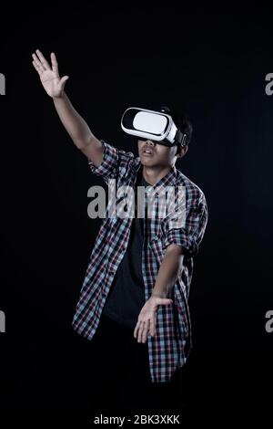 Student man wearing virtual reality goggles in studio,Smartphone using with VR headset. Stock Photo