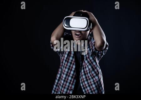 Student man wearing virtual reality goggles in studio,Smartphone using with VR headset. Stock Photo