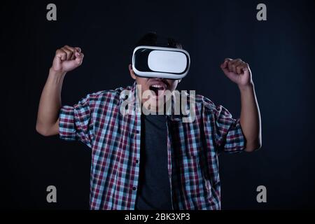 Student man wearing virtual reality goggles in studio,Smartphone using with VR headset. Stock Photo