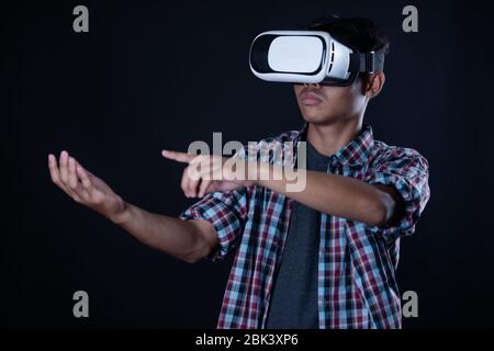Student man wearing virtual reality goggles in studio,Smartphone using with VR headset. Stock Photo