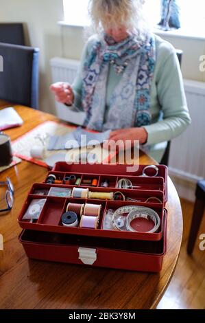 Woman at home sewing with sewing box during coronavirus lockdown Stock Photo