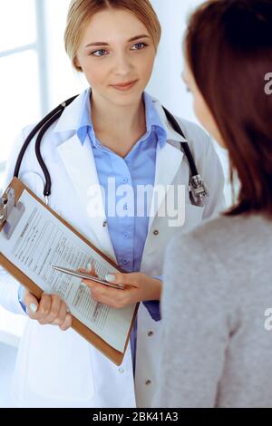 Young woman doctor and patient at medical examination at hospital office. Blue color blouse of therapist looks good. Medicine and healthcare concept Stock Photo